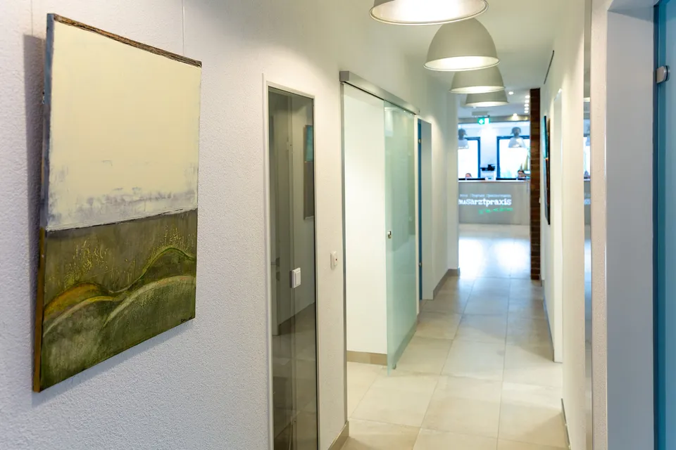 Heller Flur der Praxis mit Kunstwerken.